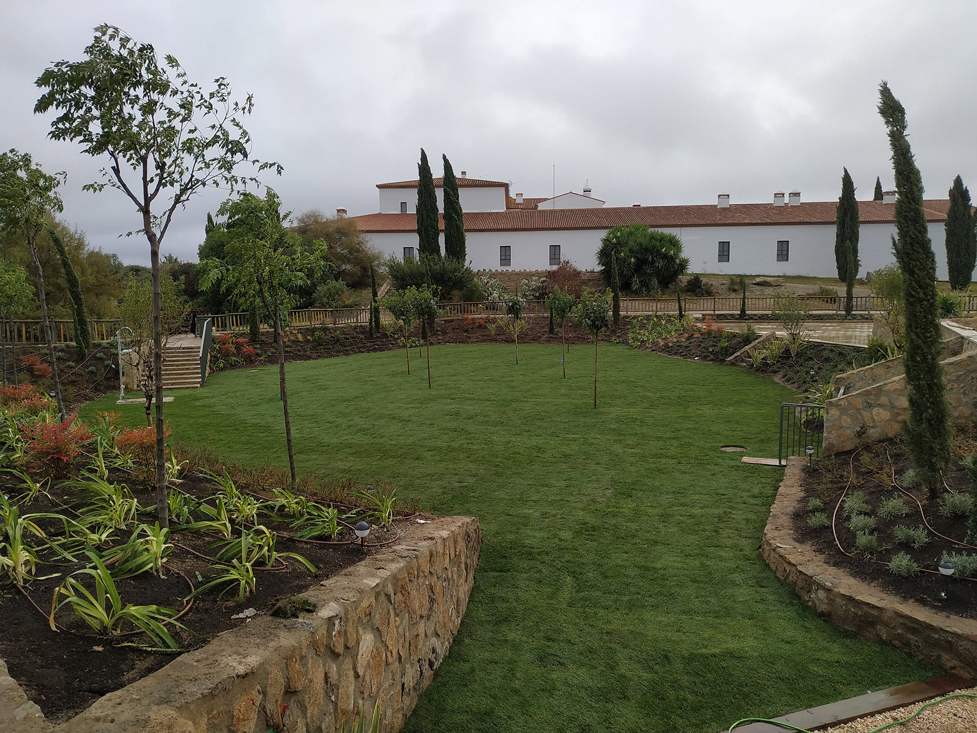 Paisajismo en Toledo en jardín residencial con césped, piedra y cipreses